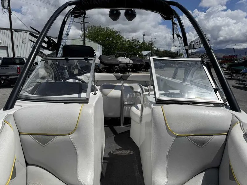 Slide: The Image of 2006 Tigé 21i boat interior with white seating and open windshield under a cloudy sky. - 12