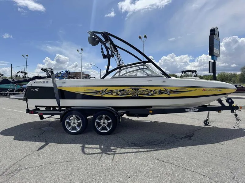 Slide: The Image of 2006 Tigé 21i boat on trailer, yellow and black design, parked outdoors under cloudy sky. - 5