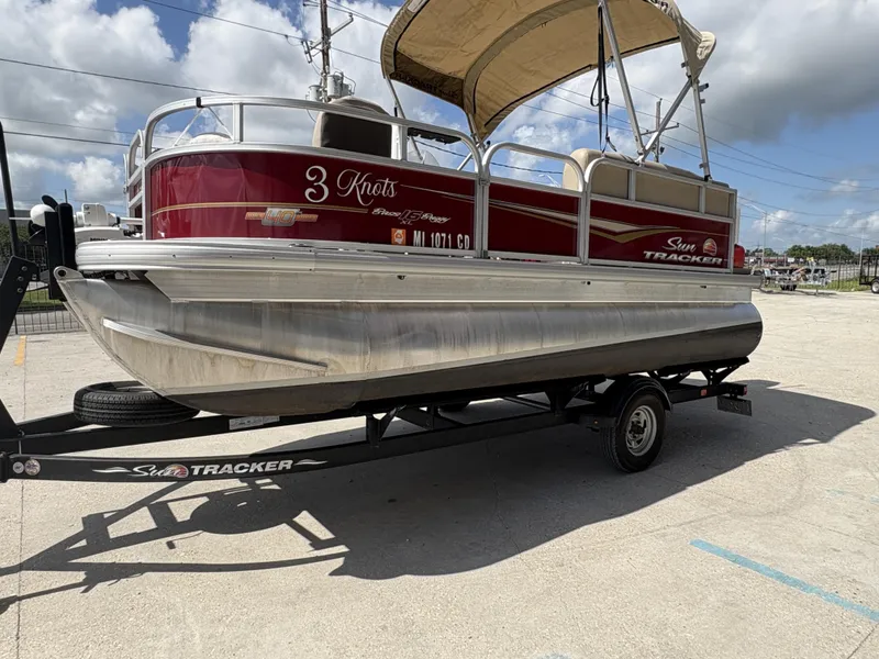 Slide: The Image of 2023 Sun Tracker Bass Buggy 16 XL pontoon boat on trailer, parked outdoors. - 3