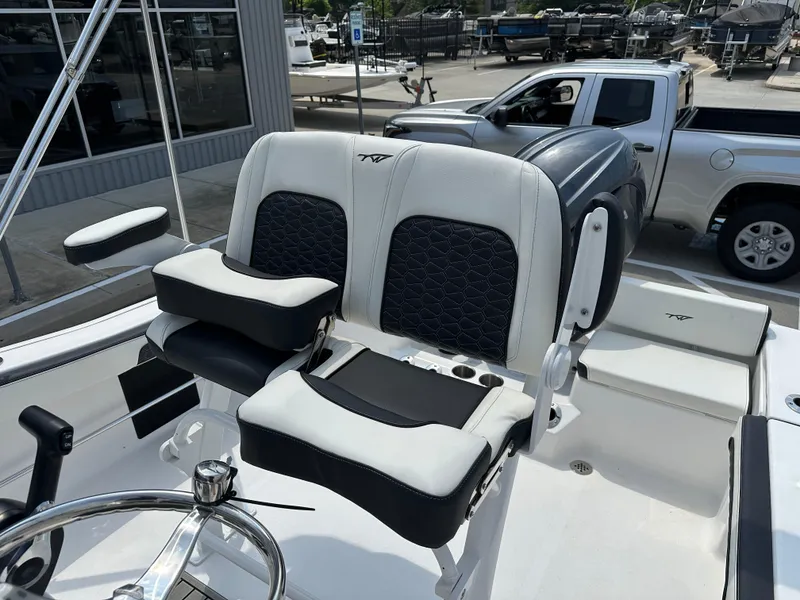 Slide: The Image of 2025 Tidewater 198CC boat interior with dual seats and steering wheel, parked near a truck. - 17