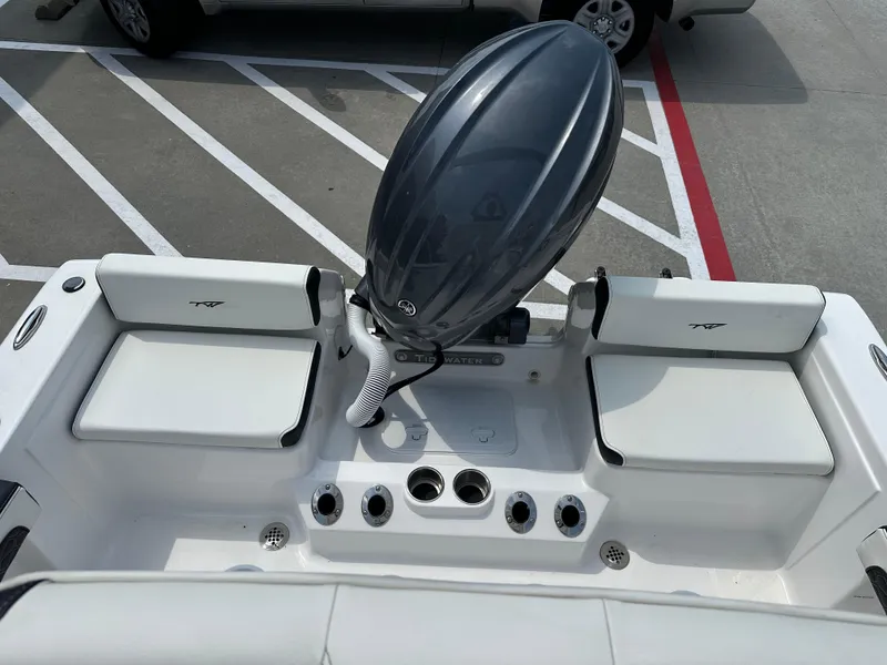 Slide: The Image of 2025 Tidewater 198CC boat interior with seating and motor, parked on a concrete surface. - 18