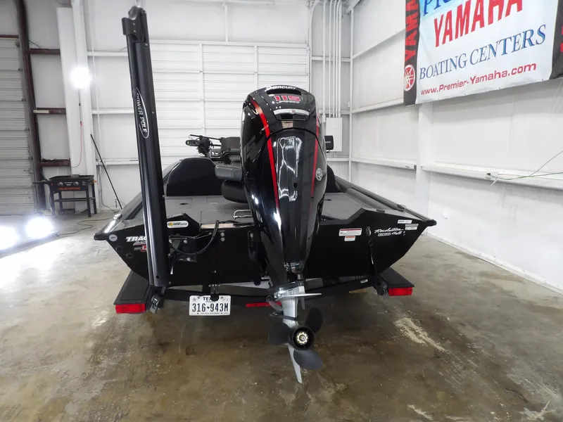Slide: The Image of 2023 Tracker PRO190TX boat in showroom, rear view with motor and trailer. - 6