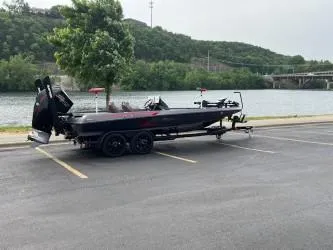 The Image of 2024 iKon LX 21 boat on trailer by a scenic riverside parking lot. - 0