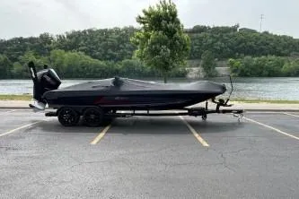 Slide: The Image of 2024 iKon LX 21 boat on trailer by a river, parked in a lot. - 2