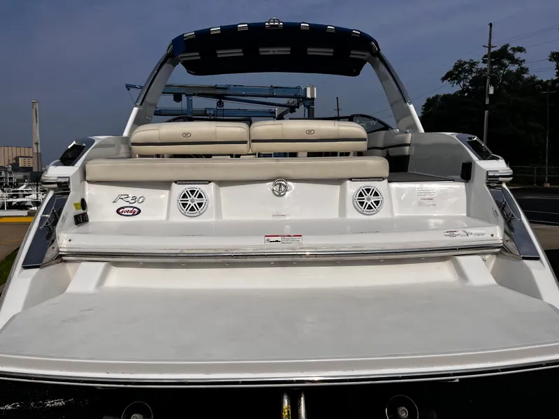 Slide: The Image of 2016 Cobalt R30 boat rear view with seating and speakers, docked outdoors. - 28
