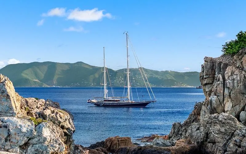 Slide: The Image of Sailing yacht Jongert Ketch 2002 on serene blue sea, framed by rocky cliffs. - 23