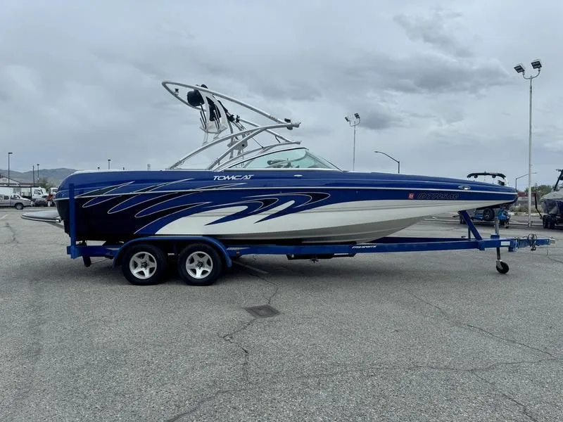Slide: The Image of 2007 MB TOMCAT boat on trailer, blue and white design, parked outdoors. - 5