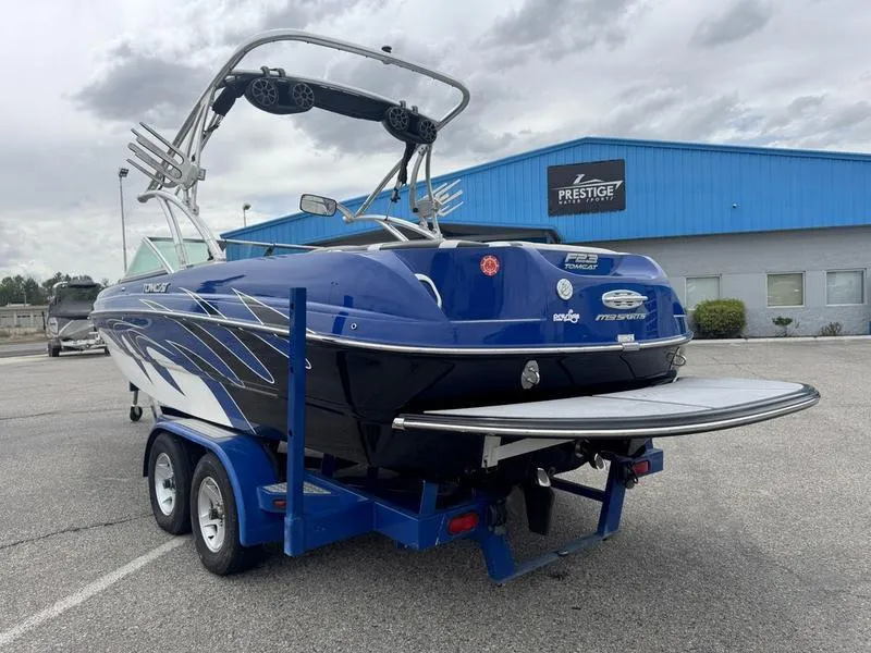 Slide: The Image of 2007 MB TOMCAT boat on trailer, parked outside a blue building under cloudy skies. - 6