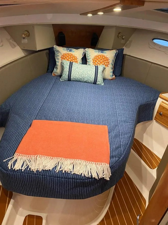 Slide: The Image of Cozy cabin interior of 2020 Cutwater C-32 CB with blue bedding and decorative pillows. - 25