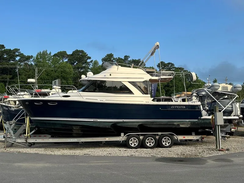 Slide: The Image of 2020 Cutwater C-32 CB boat on trailer, parked outdoors with trees in background. - 3