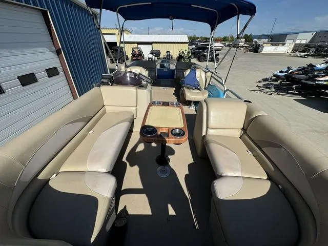 Slide: The Image of 2014 SunCatcher V322 RC pontoon boat with beige seating and blue canopy in a storage area. - 31