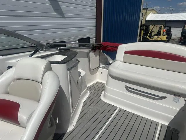 Slide: The Image of 2008 Chaparral Sunesta 224 boat interior with white and red seating, docked near a building. - 14