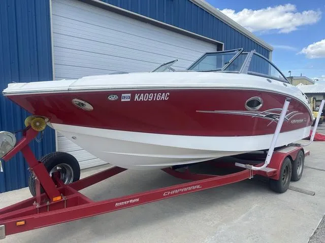 Slide: The Image of 2008 Chaparral Sunesta 224 boat on trailer, red and white, parked by blue building. - 2