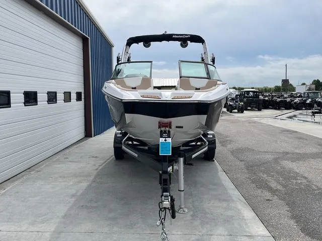 Slide: The Image of 2024 MasterCraft XT20 boat on trailer, parked outside a warehouse. - 3