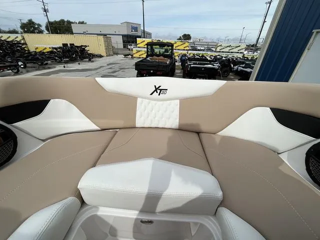 Slide: The Image of 2024 MasterCraft XT20 boat interior with beige and white seating in a showroom. - 40