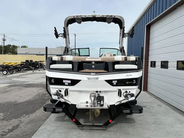 Slide: The Image of 2024 MasterCraft XT20 boat, rear view, parked near a warehouse. - 6