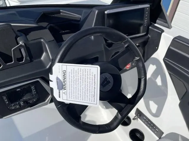 Slide: The Image of 2024 Axis Wake Research T220-R boat dashboard with steering wheel and warning tag. - 16