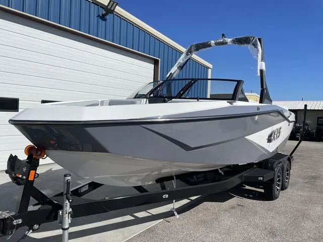 Slide: The Image of 2024 Axis Wake Research T220-R boat on trailer, parked outside a warehouse. - 2