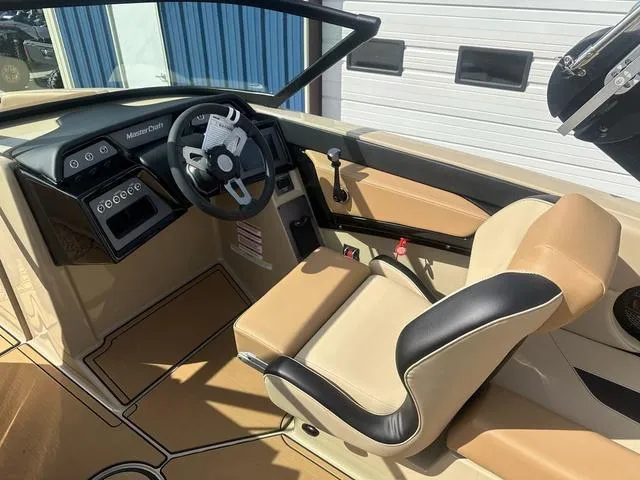 Slide: The Image of 2024 MasterCraft NXT21 boat interior with beige and black seating, modern dashboard, and steering wheel. - 14
