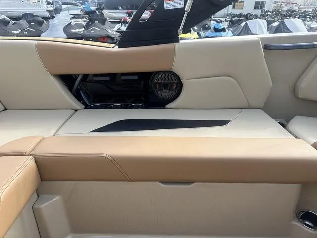 Slide: The Image of 2024 MasterCraft NXT21 boat interior with beige and tan seating, featuring a speaker and cup holders. - 25