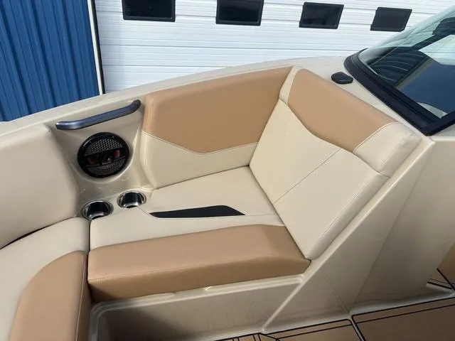 Slide: The Image of 2024 MasterCraft NXT21 boat interior with beige and tan seating, cup holders, and speaker. - 30