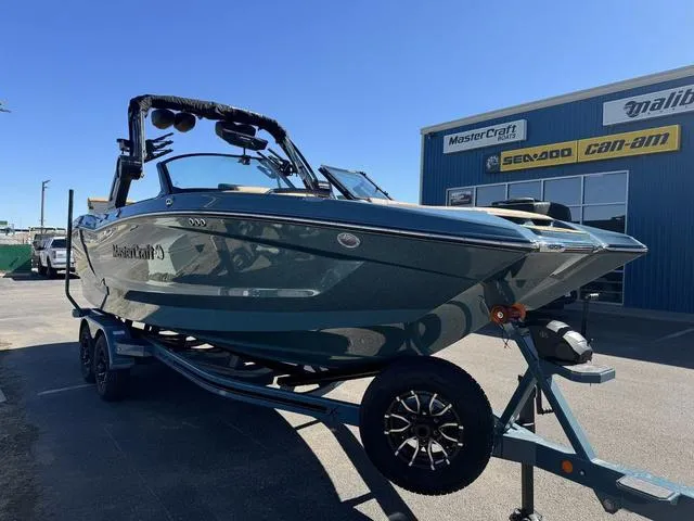 Slide: The Image of 2025 MasterCraft X24 boat on trailer, parked outside dealership under clear blue sky. - 4