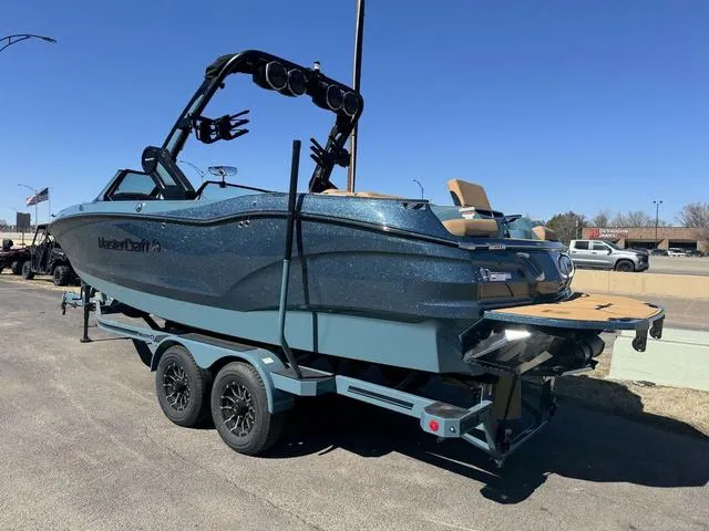 Slide: The Image of 2025 MasterCraft X24 boat on trailer, blue finish, parked outdoors under clear sky. - 5