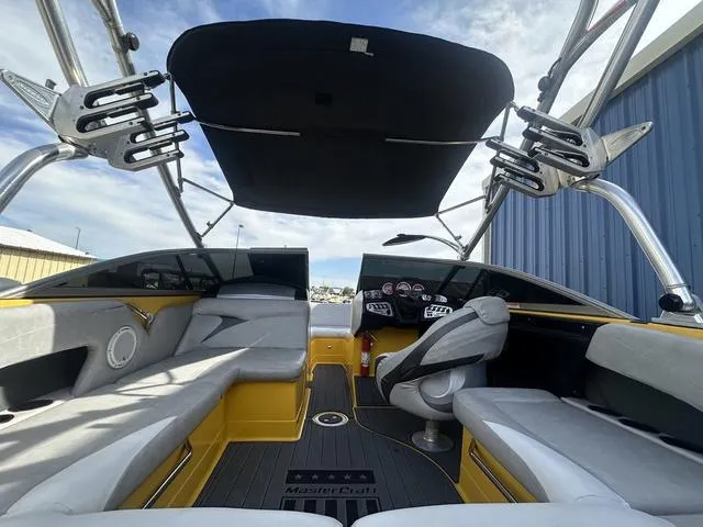 Slide: The Image of 2006 MasterCraft X2 boat interior with gray seating, black canopy, and modern dashboard. - 19