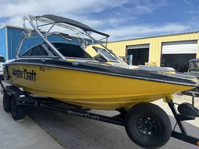Slide: The Image of 2006 MasterCraft X2 yellow boat on trailer, parked outside industrial building. - 4