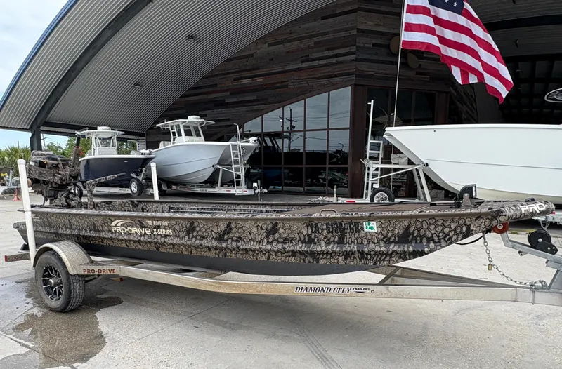 Slide: The Image of 2024 Pro-Drive X-Series TD Edition boat on trailer, parked outside with American flag. - 1