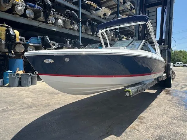 Slide: The Image of 2025 Cobalt CS22 boat in storage, blue hull with red stripe, elevated on a lift. - 6