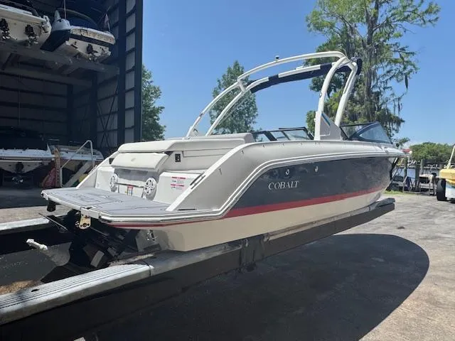 Slide: The Image of 2025 Cobalt CS22 boat on trailer, white and blue design, outdoor storage area. - 7