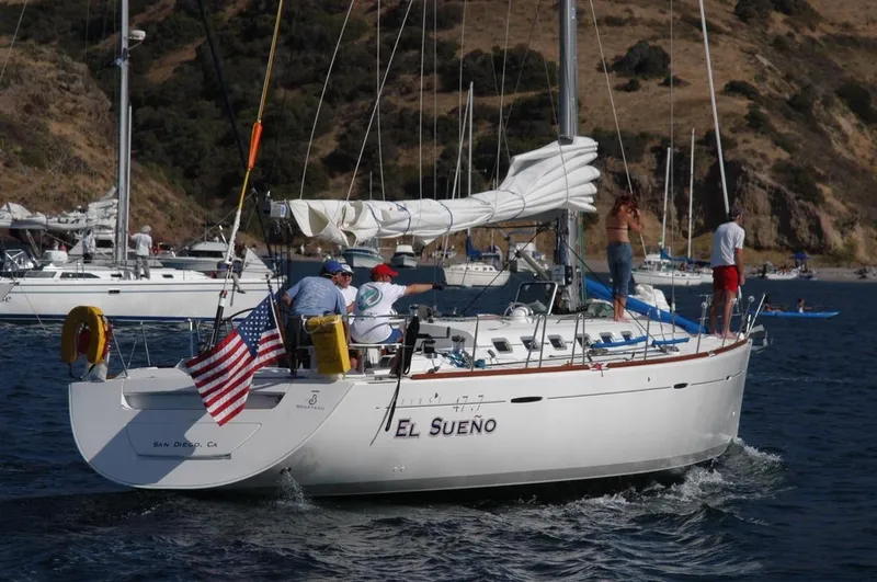 Slide: The Image of 2001 Beneteau First 47.7 sailboat "El Sueno" cruising near a scenic coastline. - 1