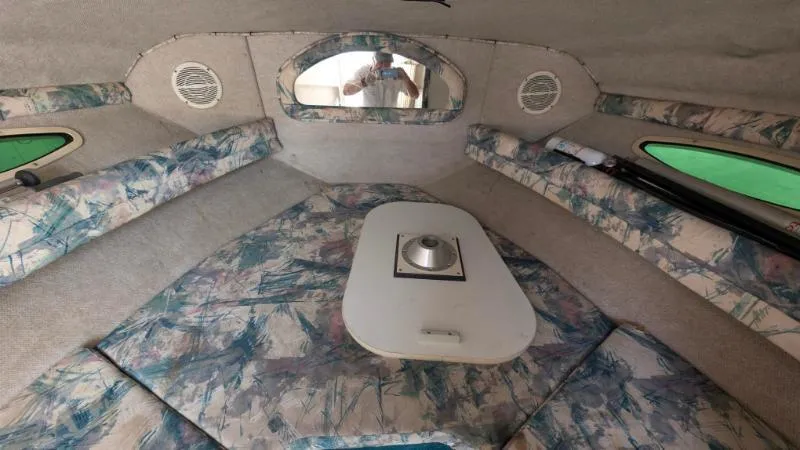 Slide: The Image of 1997 Sea Ray 215 Express Cruiser cabin interior with floral upholstery and compact table. - 10