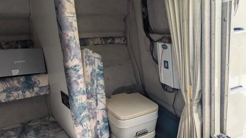 Slide: The Image of 1997 Sea Ray 215 Express Cruiser cabin interior with portable toilet and floral upholstery. - 12