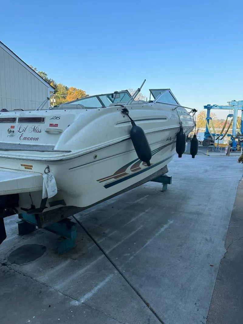 Slide: The Image of 1997 Sea Ray 215 Express Cruiser on dry dock, white hull, outdoor setting. - 16