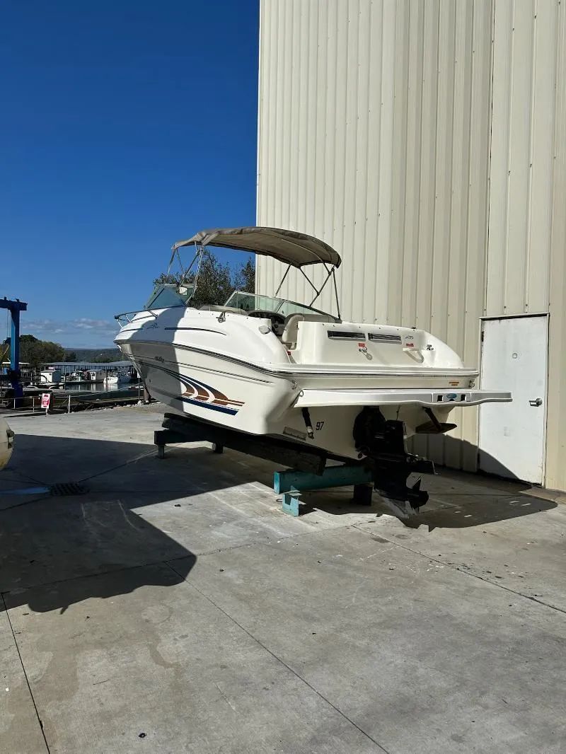 Slide: The Image of 1997 Sea Ray 215 Express Cruiser boat on dry dock, white exterior, sunny day. - 20
