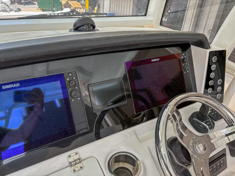 Slide: The Image of 2023 Robalo R302 boat dashboard with dual Simrad displays and steering wheel. - 10