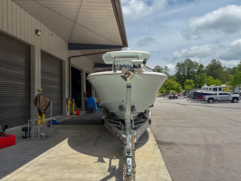 Slide: The Image of 2023 Robalo R302 boat on trailer outside a warehouse under a cloudy sky. - 5