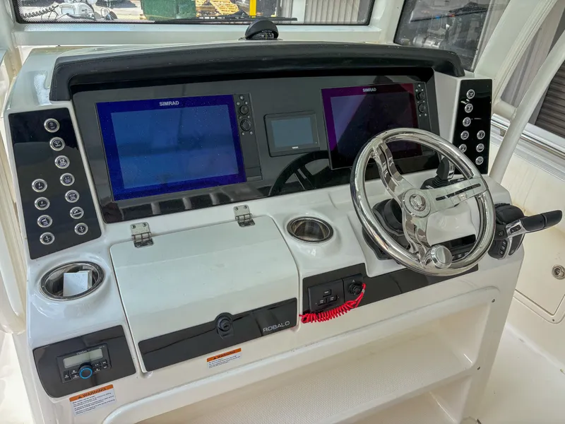 Slide: The Image of 2023 Robalo R302 boat dashboard with dual Simrad displays and steering wheel. - 8