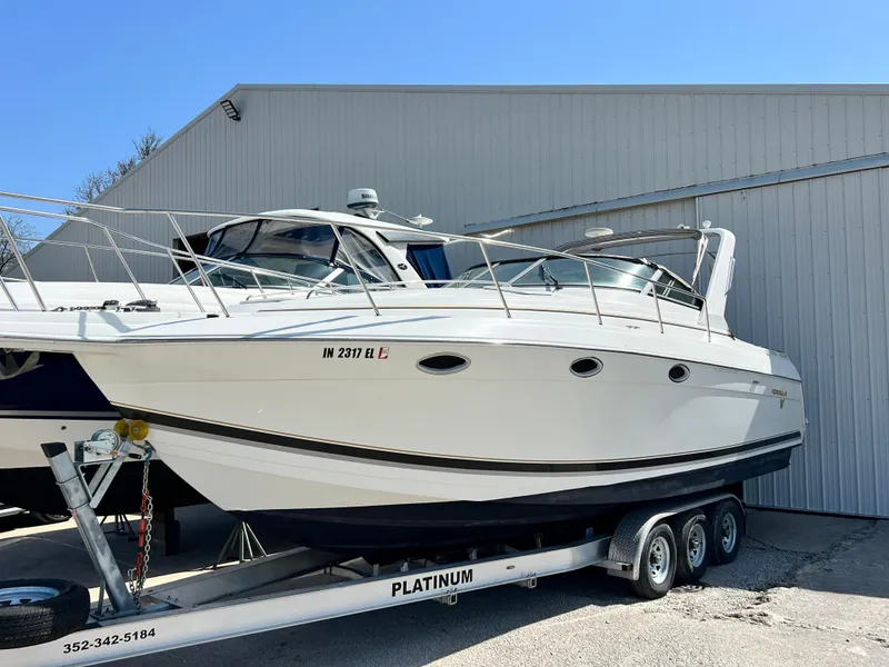 The Image of 1999 Formula 31 PC boat on trailer, parked outside a large building. - 1