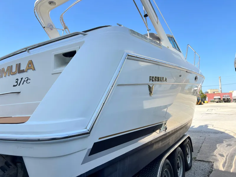Slide: The Image of 1999 Formula 31 PC boat on trailer, white exterior, docked outdoors under clear blue sky. - 5