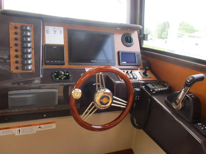 Slide: The Image of 2020 Ranger Tugs R-27 LE helm with wooden steering wheel and navigation controls. - 11