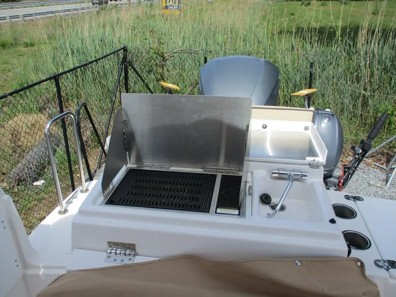 Slide: The Image of 2020 Ranger Tugs R-27 LE boat with outdoor grill and motor, surrounded by greenery. - 13
