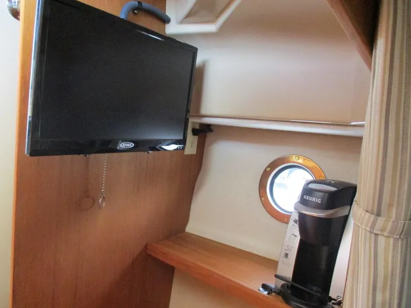 Slide: The Image of 2020 Ranger Tugs R-27 LE interior with TV, porthole, and Keurig coffee maker. - 9