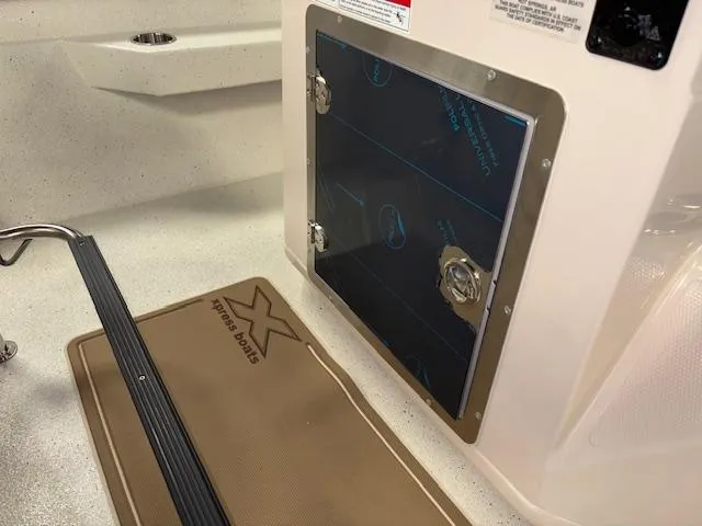 Slide: The Image of 2025 Xpress H22 Bay boat interior with storage compartment and branded mat. - 13