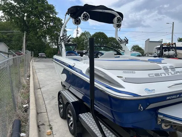 Slide: The Image of 2014 Centurion Enzo SS210 boat on trailer, parked outdoors, featuring blue and white design. - 12