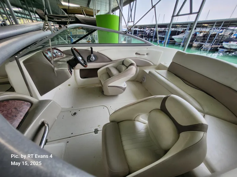 Slide: The Image of 2008 Caravelle 206LS Bow Rider interior with beige seating and steering wheel, docked at marina. - 12