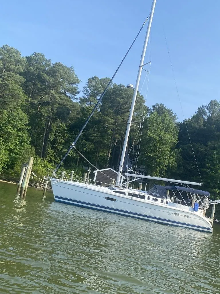 Slide: The Image of Sailboat Hunter 410, 2001 model, docked on a serene lake with lush trees. - 1