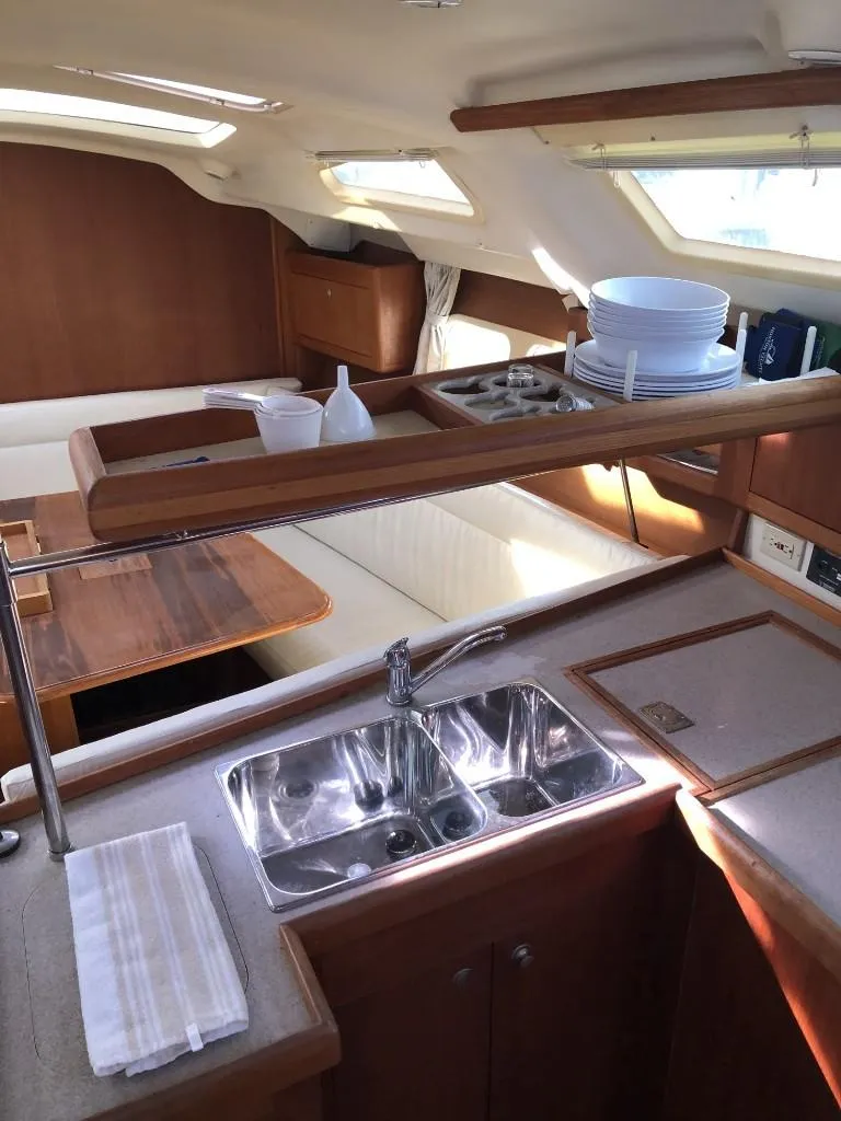 Slide: The Image of Interior of a 2001 Hunter 410 sailboat featuring a compact kitchen and dining area. - 17